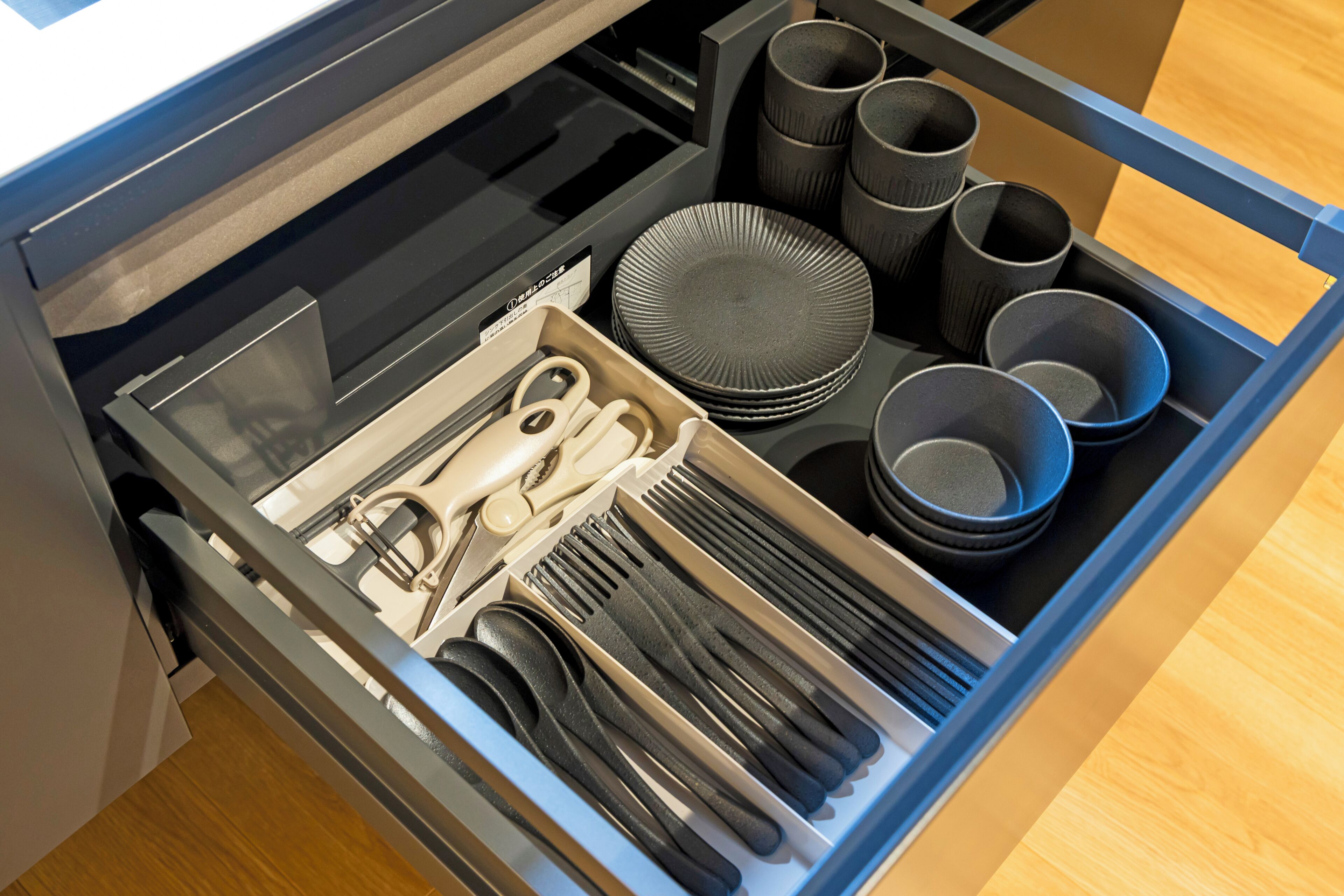 A drawer with utensils, plates, and cups.