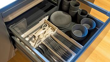 A drawer with utensils, plates, and cups.