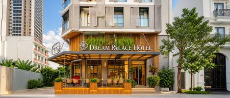 A hotel with a modern facade, a covered outdoor seating area, and a prominent entrance.