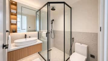 A modern bathroom with a glass-enclosed shower, a white sink, and a toilet.