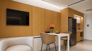 Una cocina moderna con una televisión de pantalla plana, una mesa de comedor con sillas y un refrigerador.