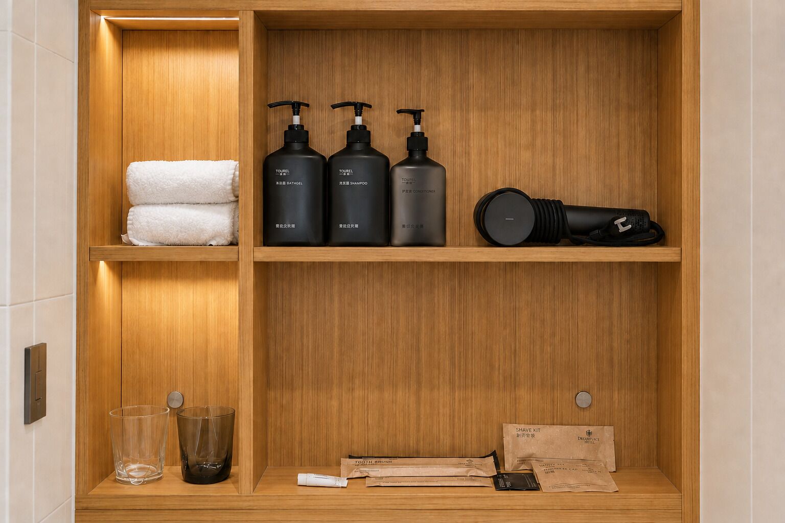 A wooden shelf with toiletries including a towel, bottles of shampoo and conditioner, a hairdryer, and a shaving kit.