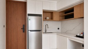 Una cocina moderna con refrigerador de acero inoxidable, armarios blancos y una salpicadera de mármol.