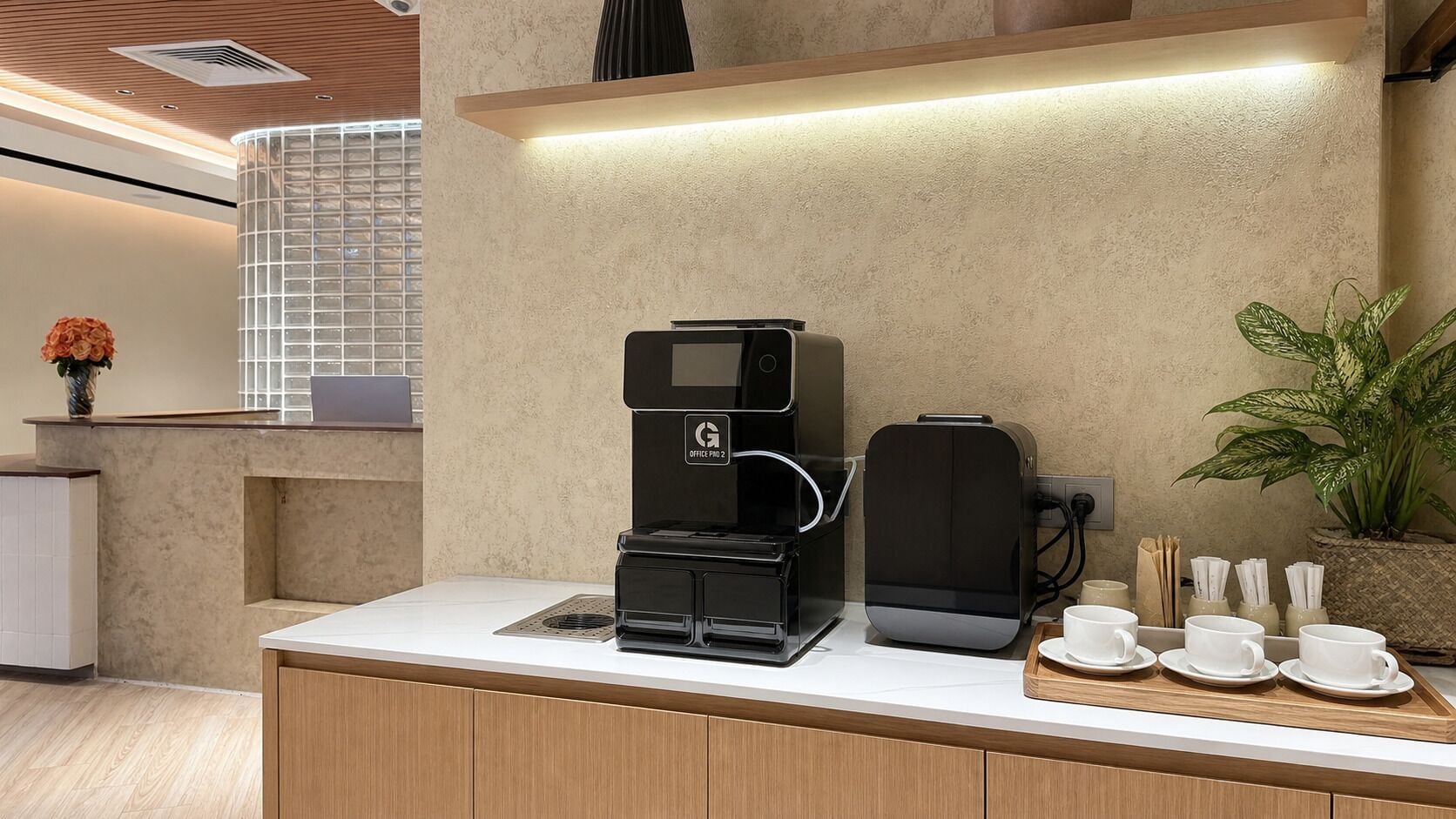 Una cocina moderna con cafetera, hervidor y una bandeja con tazas y platillos.