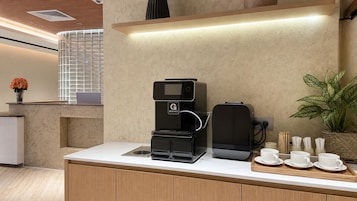 Una cocina moderna con cafetera, hervidor y una bandeja con tazas y platillos.