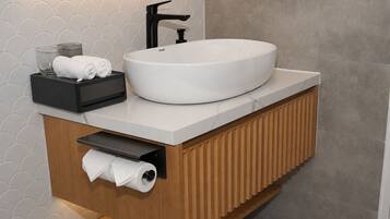 Une salle de bain moderne avec un lavabo rond blanc, un robinet noir et un distributeur de serviettes.