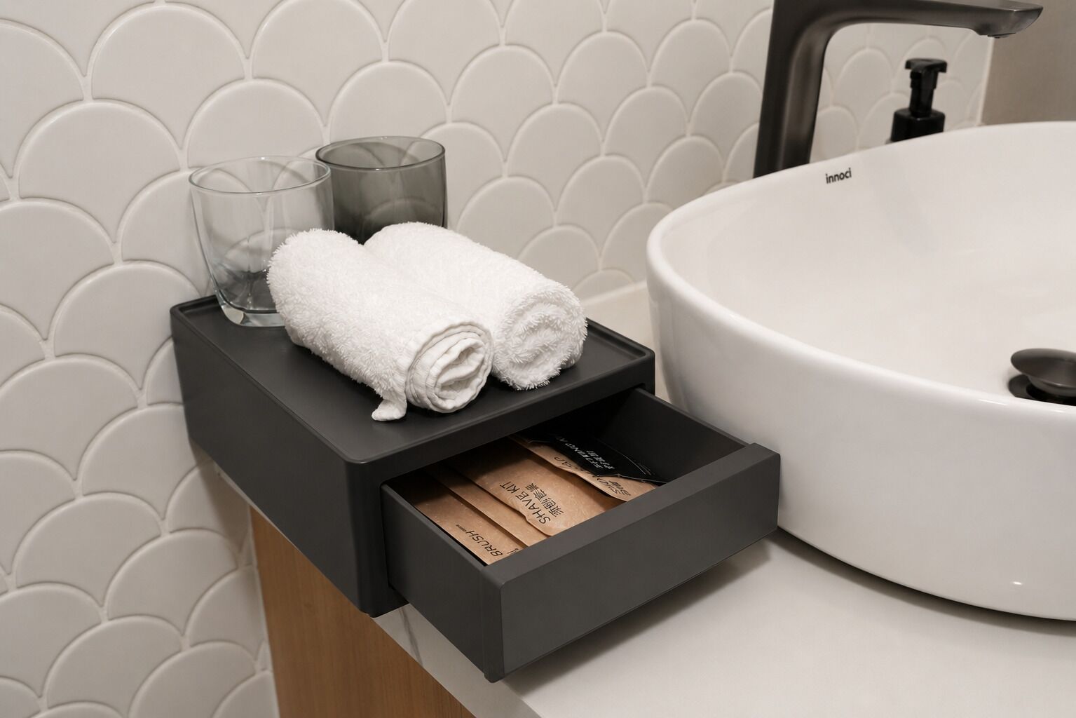 A bathroom with a white sink, a towel warmer, and a storage drawer with toiletries.