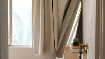 Een kamer met een groot raam, een spiegel, een houten dressoir en een kleine plant.
