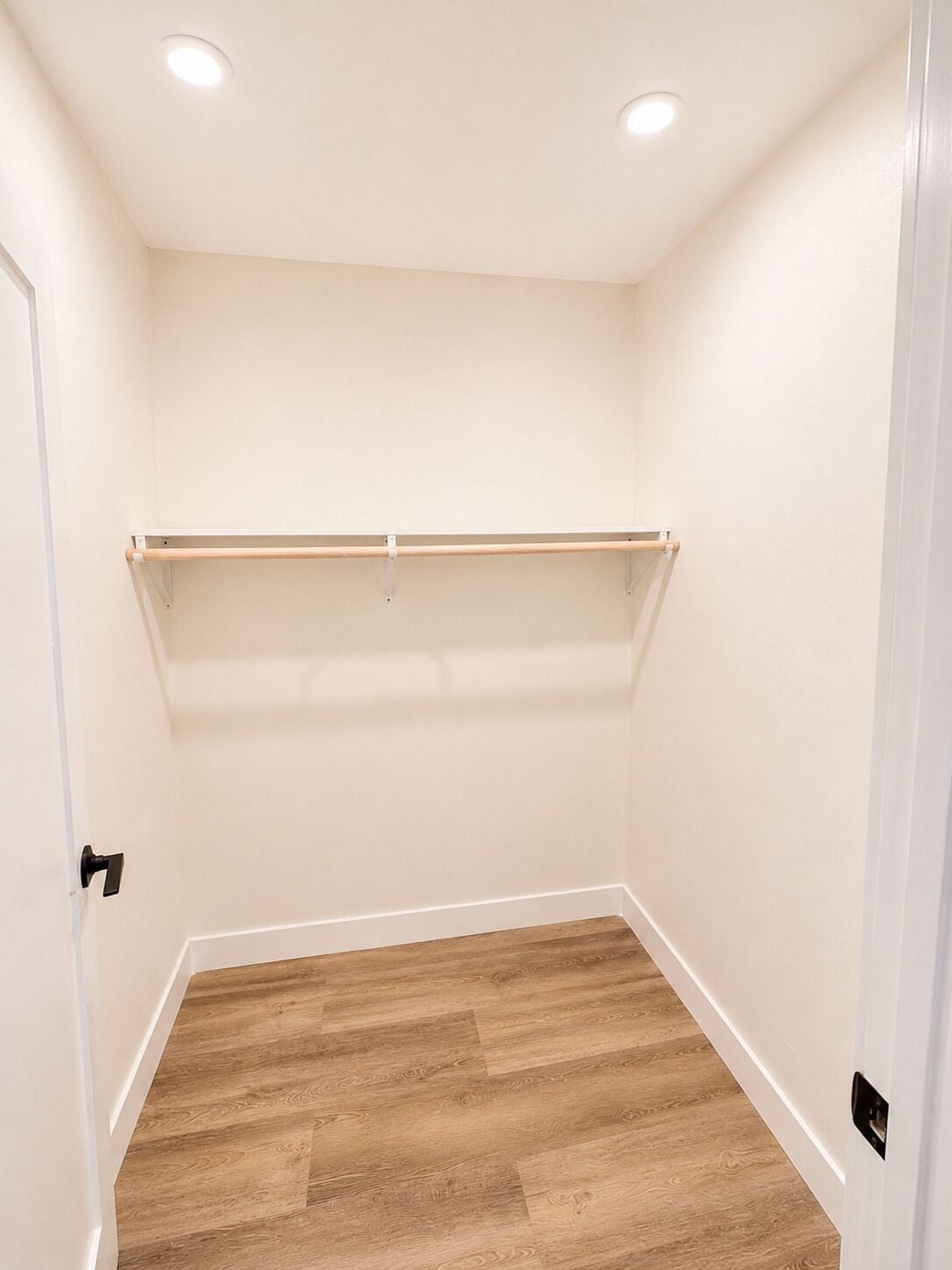 A room with a wooden floor, white walls, and a ceiling with recessed lighting.