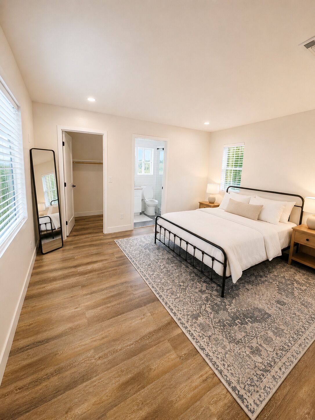 A bedroom with a bed, bedside tables, a mirror, and a door leading to a bathroom.