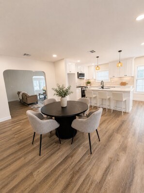 Une cuisine moderne avec des meubles blancs, un îlot central et des luminaires suspendus.