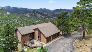 A two-story building with a deck, surrounded by mountains and trees. - Trail's End - 22-zone3197 3 Bedroom Condo (Estes Park)