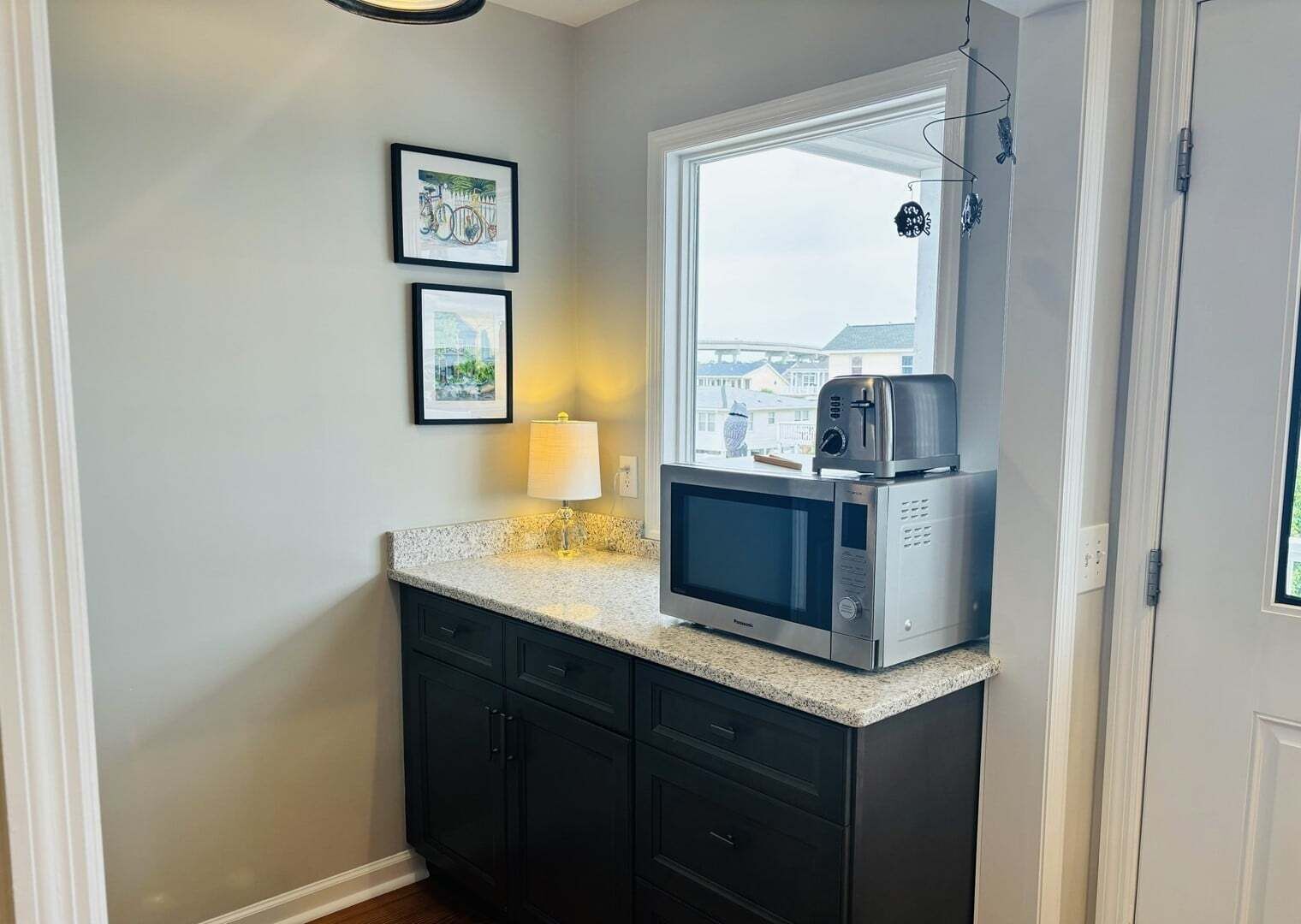 Une petite cuisine équipée d’un four à micro-ondes, d’une petite fenêtre et de deux tableaux encadrés au mur.