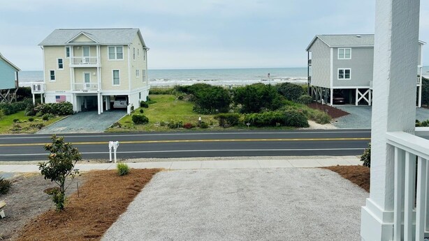 A coastal residential area with two houses, a road, and a view of the ocean. - Live Oaks / 127 Ocean Blvd East 4 Bedroom Home (Supply)