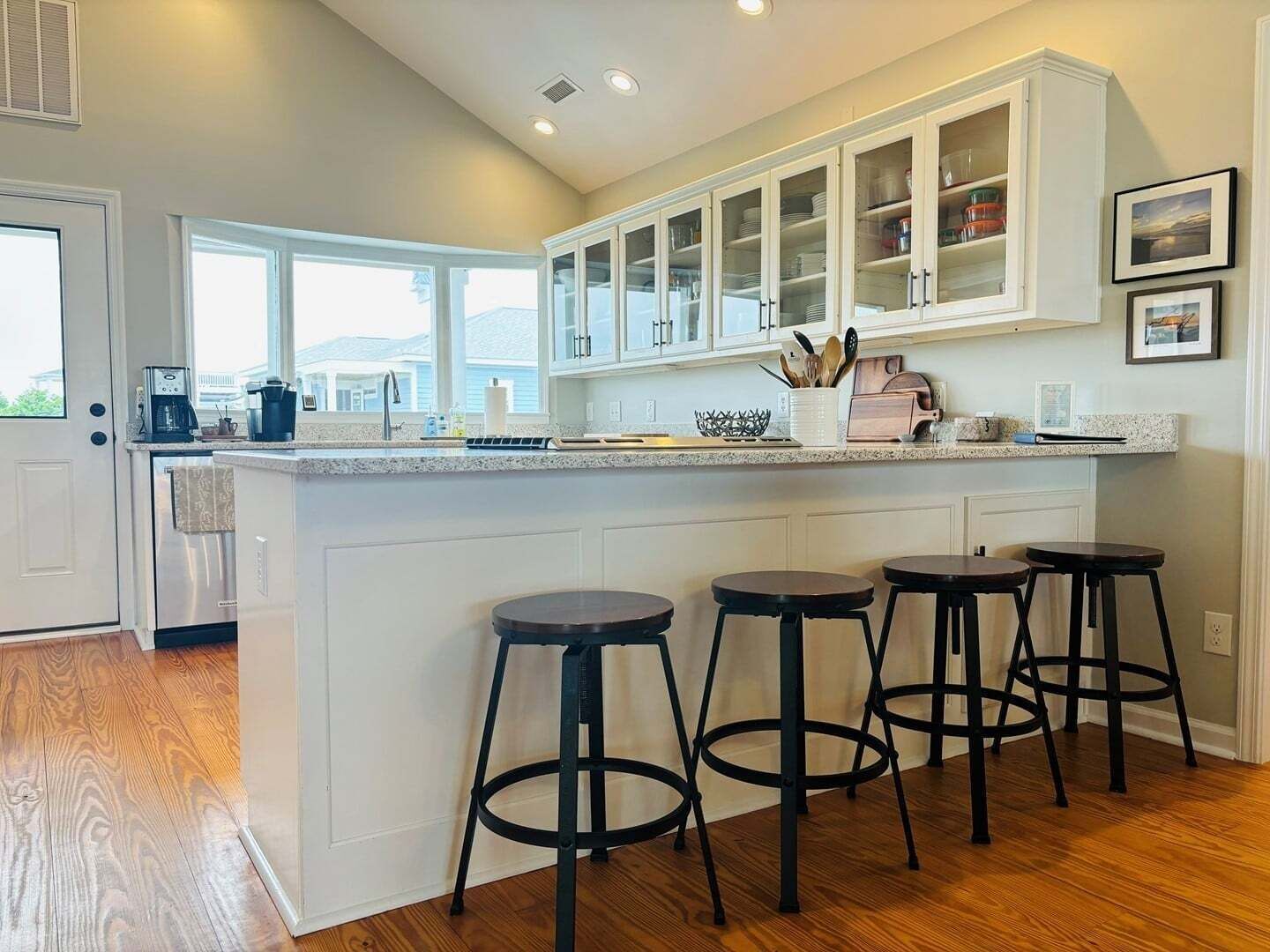 A kitchen with a central island, bar stools, and a view of the outdoors.