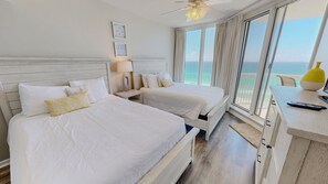 A hotel room with two beds, a nightstand, a lamp, a window with a view of the sea, and a ceiling fan. - Silver Beach 0902e 2 Bedroom Condo (Destin)