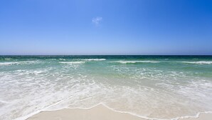 En strand med kristallklart blått vatten och en sandstrand.