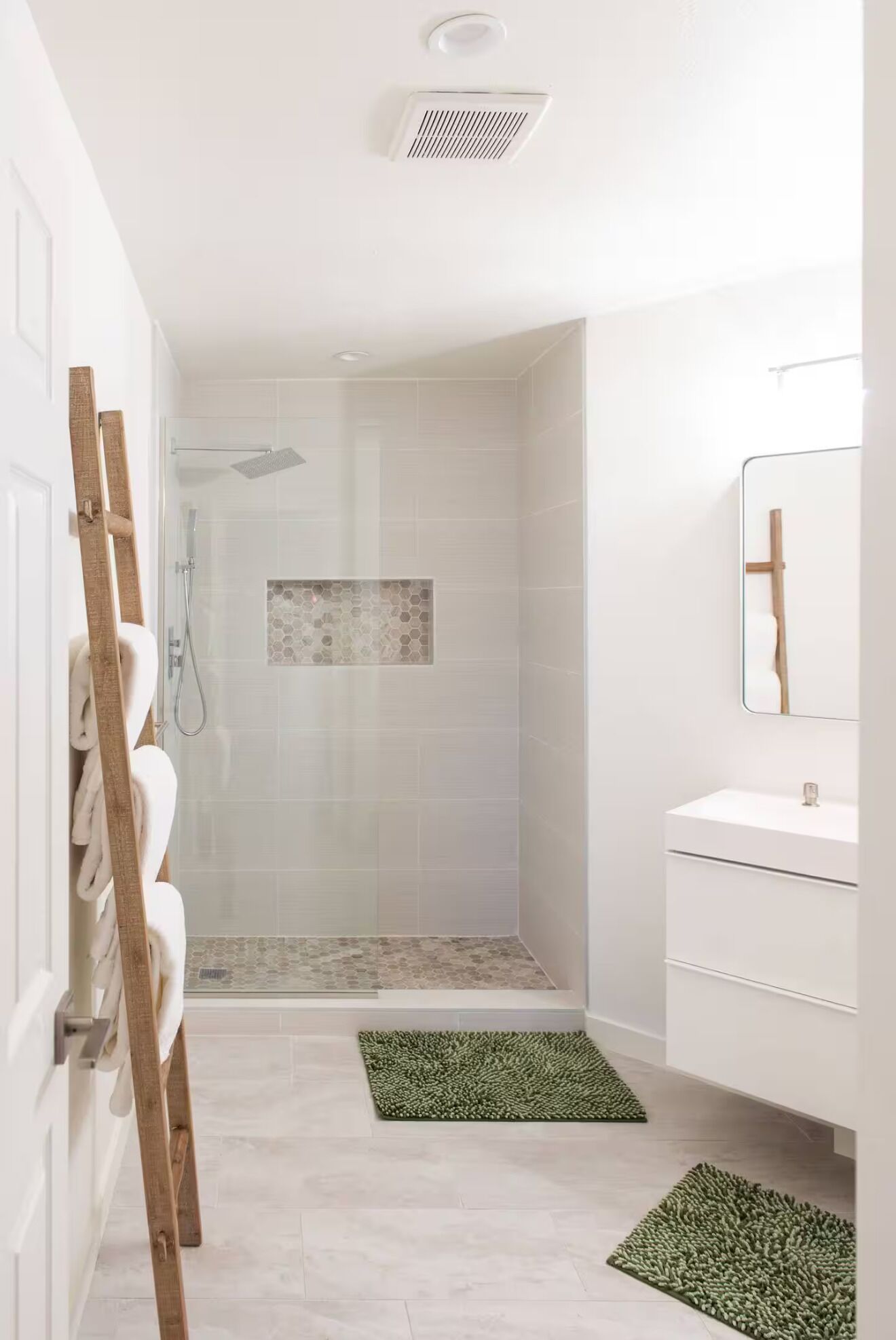 Een moderne badkamer met een douche, een wit wastafelmeubel en een spiegel.
