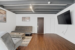 A modern living room with a sofa, a coffee table, and a TV mounted on the wall.