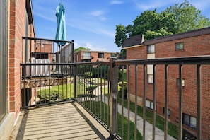 A courtyard with a metal fence, brick buildings, and a blue umbrella.