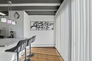 A modern kitchen with a marble countertop, a coffee machine, and a wall-mounted clock. - Quiet Flat Near Philly - Full Chef's Kitchen 1 Bedroom Apts (Glenolden)