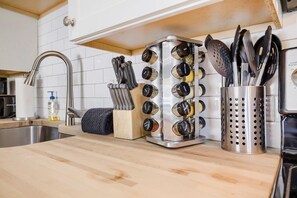 Uma cozinha com pia de aço inoxidável, escorredor de facas, temperos e suporte para utensílios.