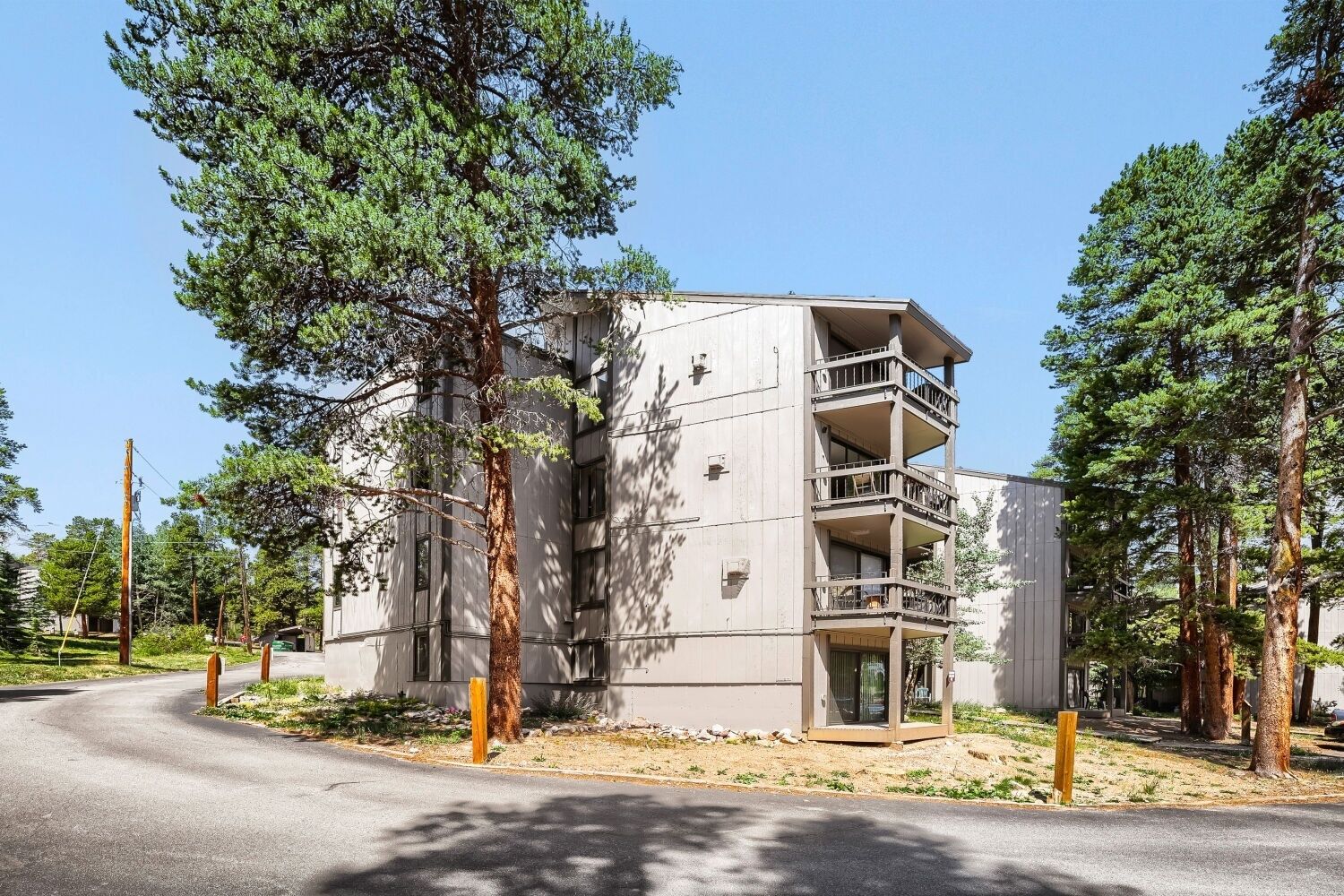 A multi-story building with balconies, surrounded by trees.