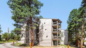 Un edificio a più piani con balconi, immerso nel verde.