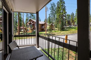 A balcony with a woven chair and a view of a residential area with houses and trees. - Gold Camp F97 2 Bedroom Condo (Breckenridge)