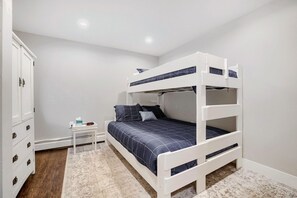 A bunk bed with a white frame, a bedside table with a clock, and a wardrobe with multiple drawers. - Gold Camp F97 2 Bedroom Condo (Breckenridge)
