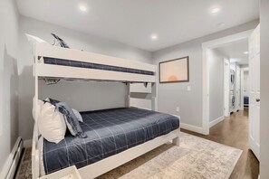 Ein Stockbett mit Kopfteil, ein Nachttisch und ein an der Wand befestigtes Regal.