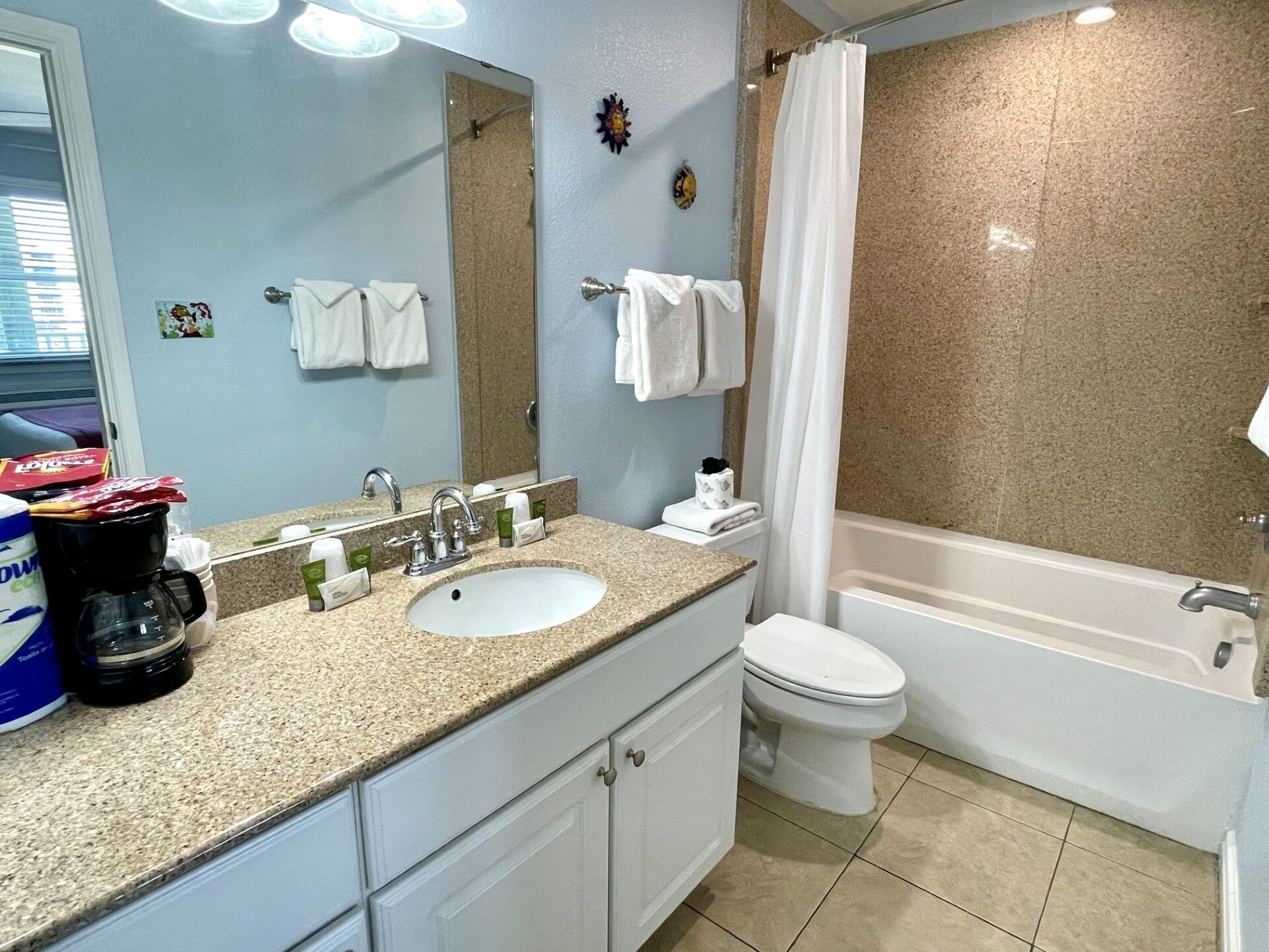 Une salle de bain avec un lavabo, des toilettes et une baignoire. Des serviettes sont accrochées au mur et il y a un rideau de douche.