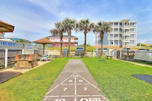 A shuffleboard court with numbers 1 to 10 and "OFF" at the end, surrounded by grass and palm trees. - Beachgate Condo Suites And Hotel 532a+532b 2 Bedroom Condo (Port Aransas)