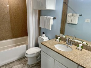 A bathroom with a bathtub, toilet, sink, and a mirror. - Beachgate Condo Suites And Hotel 517a+517b 2 Bedroom Condo (Port Aransas)