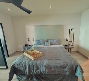 A modern bedroom with a large bed, bedside tables, a mirror, and a ceiling fan. - Ross Rosarito (Playas de Rosarito)