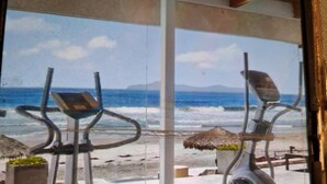 A gym with exercise equipment and a view of the beach. - Ross Rosarito (Playas de Rosarito)