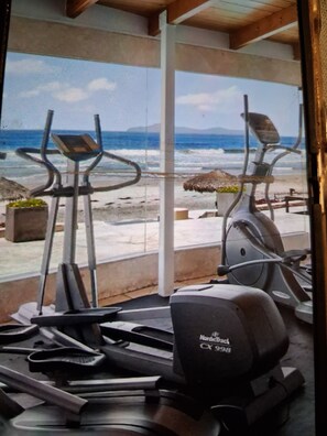 A gym with exercise equipment and a view of the beach. - Ross Rosarito (Playas de Rosarito)