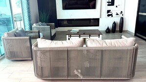 A modern living room with a large sofa, a coffee table, and a flat-screen TV mounted on the wall. - Ross Rosarito (Playas de Rosarito)