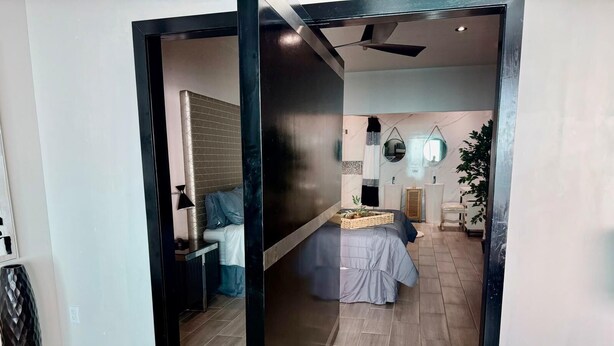 A modern bedroom with a bed, bedside tables, a mirror, and a potted plant. - Ross Rosarito (Playas de Rosarito)