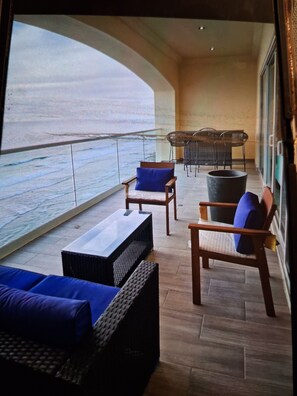A balcony with wicker furniture, a table, and a view of the sea. - Ross Rosarito (Playas de Rosarito)