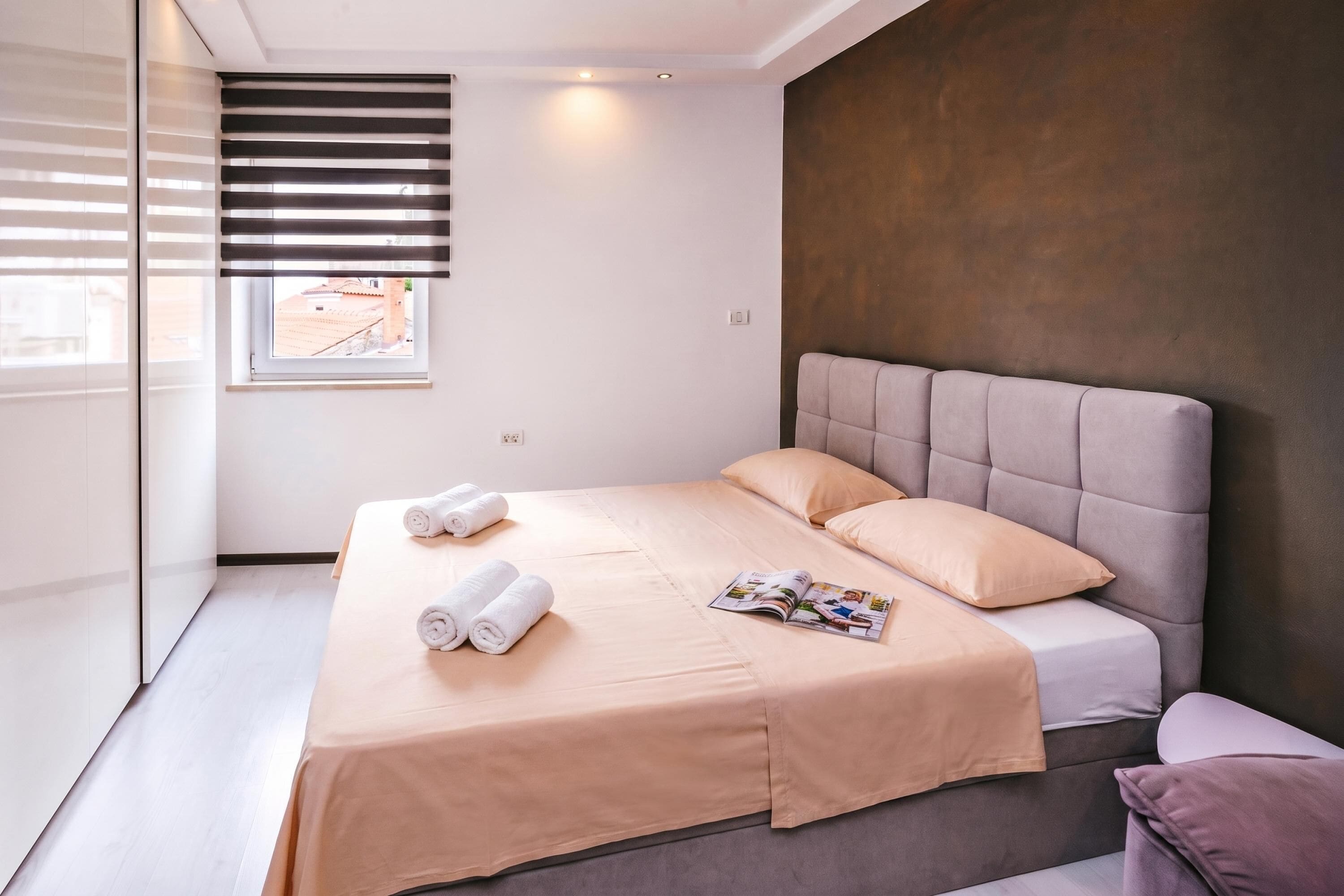 Una camera da letto moderna con un letto, cuscini e una rivista sul letto.