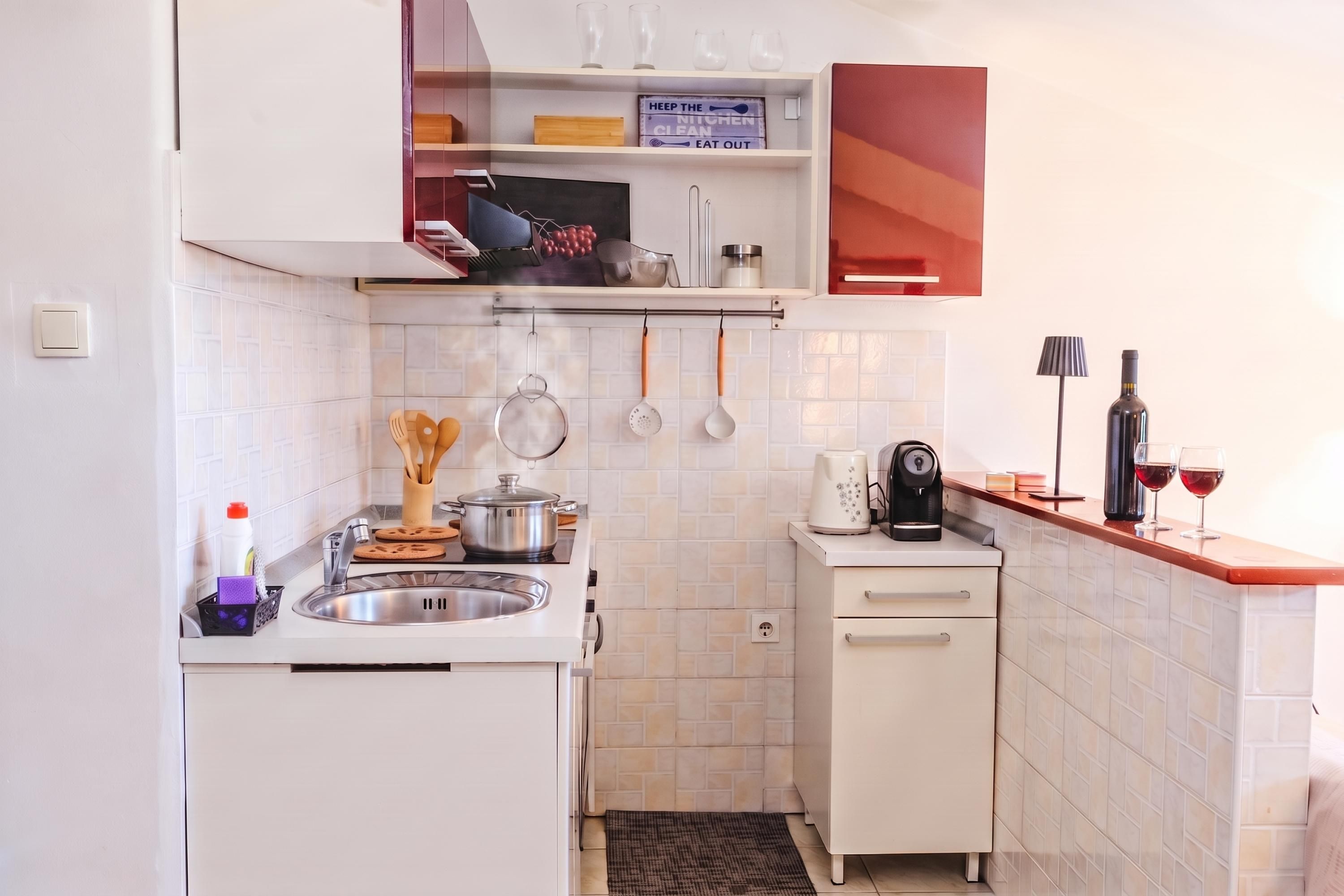 A compact kitchen with a sink, stove, and a coffee maker.