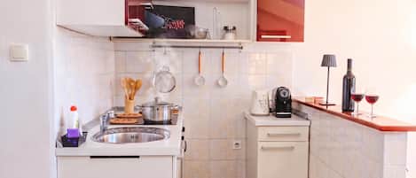 A compact kitchen with a sink, stove, and a coffee maker.