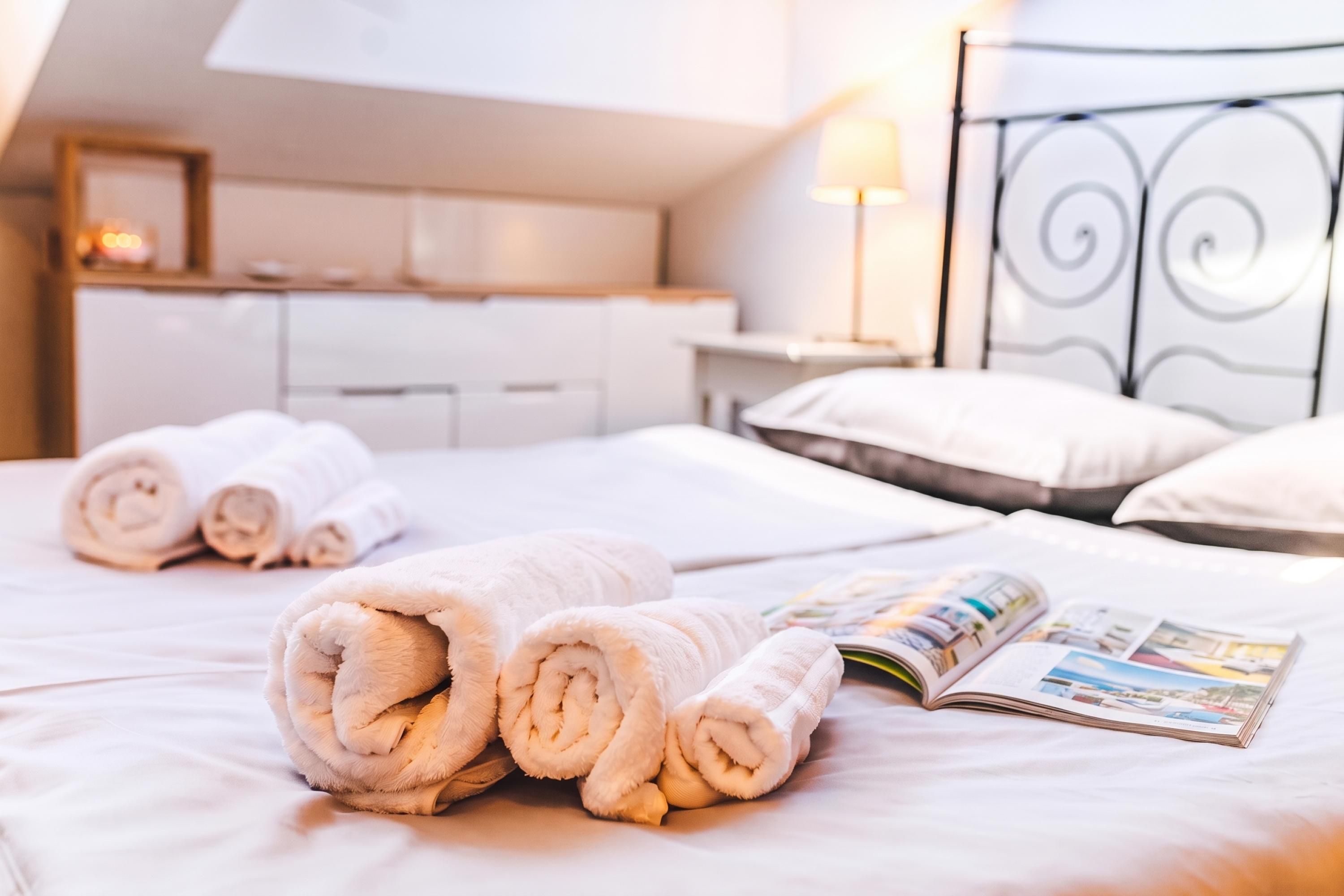 Un lit bien fait, avec des serviettes pliées et un magazine ouvert.