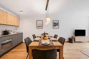 A modern kitchen with a dining area, wooden cabinets, a flat-screen TV, and artwork on the walls. - Residenza Castanea 104 San Bernardino Alpine Apartments, San Bernardino, Switzerland (San Bernardino)