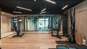 Une salle de sport moderne équipée de divers appareils d’exercice, notamment des tapis de course et des appareils de musculation, ainsi qu’un grand mur entièrement recouvert de miroirs.