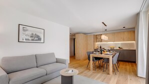 Un salon moderne avec un canapé gris, une petite table basse ronde et un coin repas comprenant une table et des chaises en bois.