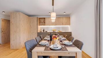 A modern dining area with a wooden table set for six, surrounded by chairs.