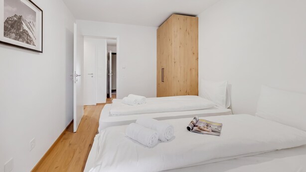 Une chambre d’hôtel moderne avec deux lits, une armoire en bois et un tableau encadré au mur.