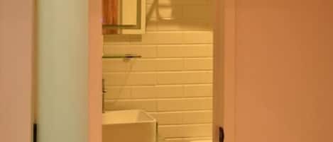 A bathroom with a toilet, sink, and mirror.
